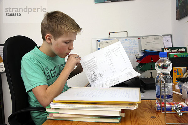 Junge  12 Jahre  macht in seinem Kinderzimmer Hausaufgaben  lernt für die Schule