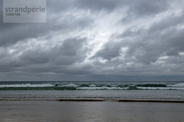 Surfer warten auf eine Welle bei stürmischem Regenwetter an der Küste von Newquay  Cornwall  England  Großbritannien  Europa