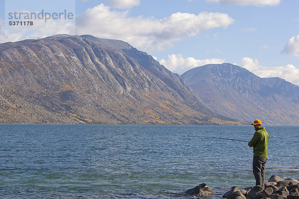 Mann beim Spinnfischen  Kusawa Lake  die Berge dahinter  Indian Summer  Herbst  Yukon Territory  Kanada