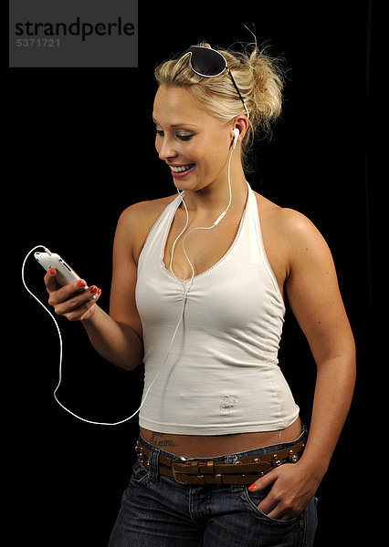 Junge Frau bedient weißes Apple iPhone  hört Musik  Ohrhörer  Kopfhörer