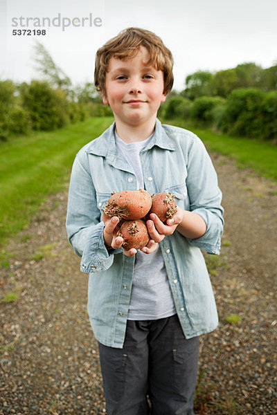 Junge mit Handvoll Kartoffeln