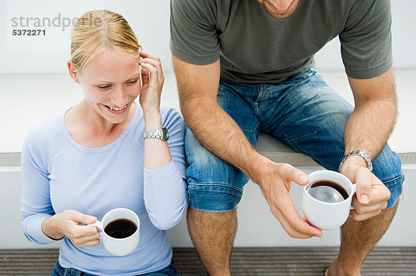 Young Couple relaxing outdoors mit Kaffee