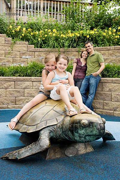 Zwei Mädchen sitzen auf der Schildkrötenstatue im Zoo.