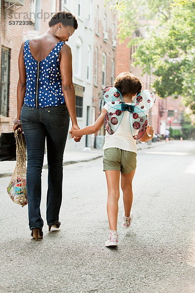 Mutter und Tochter gehen die Straße entlang  Rückansicht