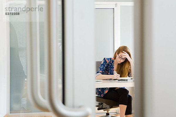 Junge Modedesignerin am Schreibtisch