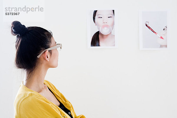 Junge Frau Modedesigner betrachten Fotos auf weiße Wand