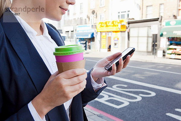 Schließung der Geschäftsfrau auf der Straße mit Kaffee und Smartphone