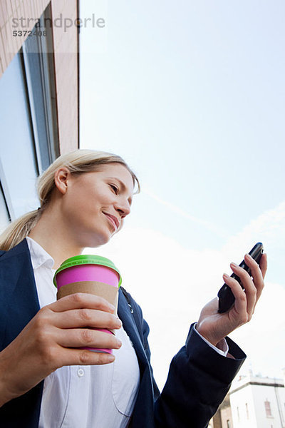 Geschäftsfrau mit Kaffee und Smartphone