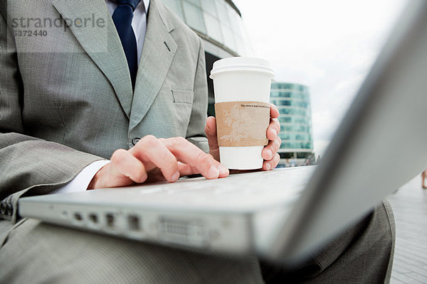 Nahaufnahme eines Geschäftsmannes mit Laptop und Kaffee im Freien