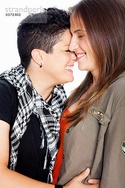 Lesbisches Paar lächelnd vor weißem Hintergrund