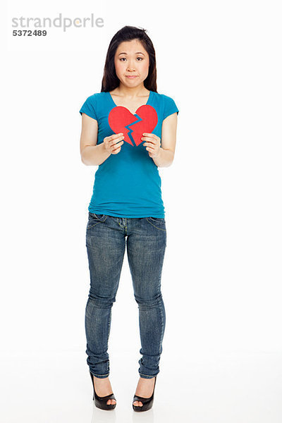 Junge Japanerin halten gebrochenes Herz against white background