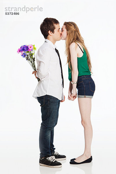 Junges Paar küsst sich vor weißem Hintergrund