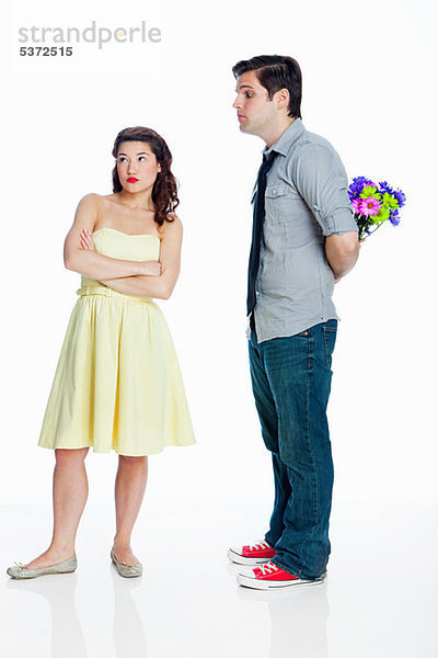 Junge Frau ignorieren Mann mit Blumen against white background