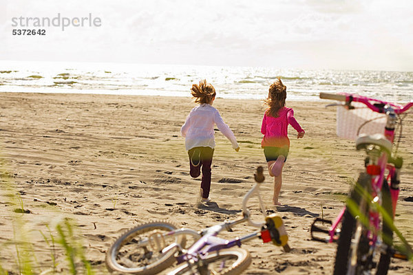 Mädchen  die am Strand in Richtung Meer rennen