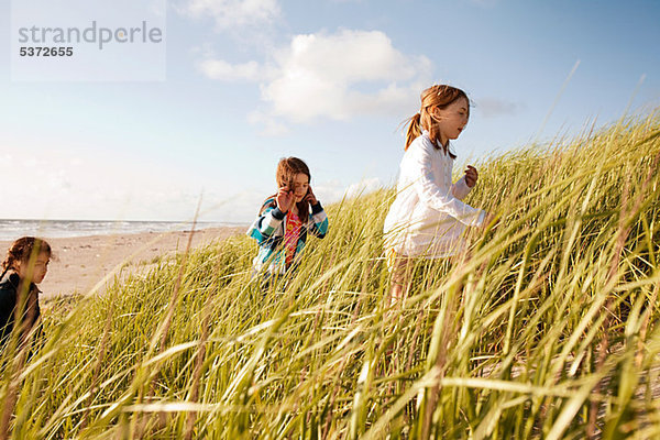 Mädchen zu Fuß durch hohes Gras am Strand