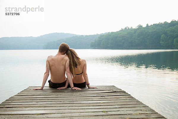 Paar auf dem Pier sitzend mit Blick auf den See