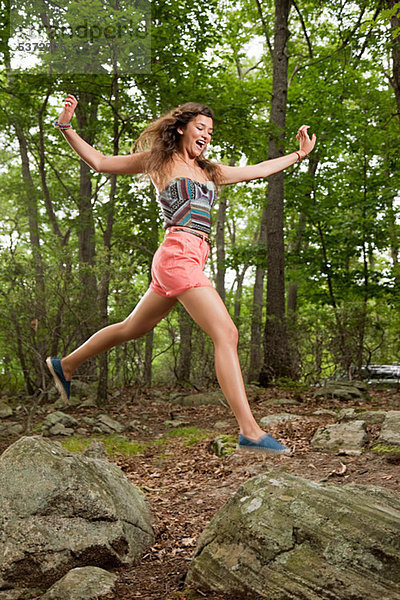 Young Hispanic Woman jumping über die Steine im Wald