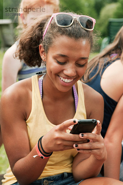 Teenage Girl looking at ein Mobiltelefon auf Land