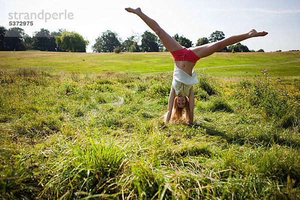 Young Woman doing einen Handstand in einem Feld