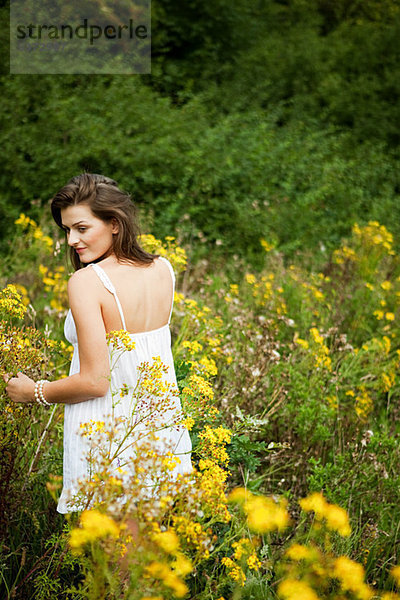 Junge Frau sammeln Blumen in der Landschaft
