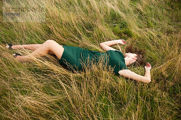 Young Woman lying down in einem Feld in ein grünes Kleid