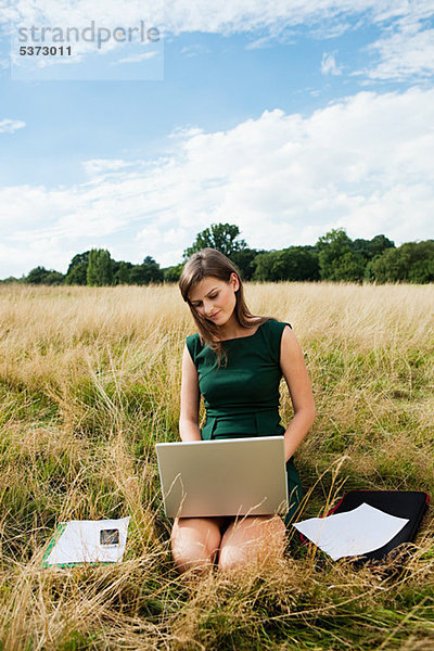 Junge Frau mit einen Laptop-Computer in der Mitte des ein Feld