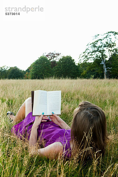 Young Woman reading ein Buch in einem Feld
