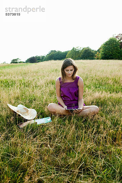 Junge Frau mit Handgerät in der Mitte eines Feldes