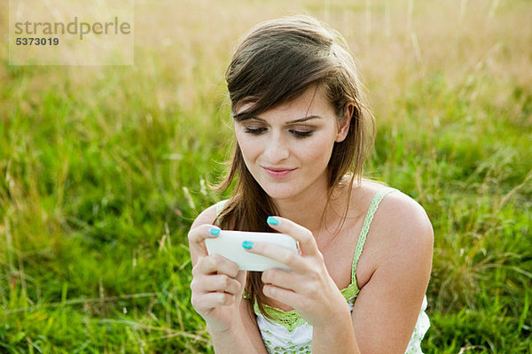 Junge Frau schaut auf ein Handgerät in einem Feld