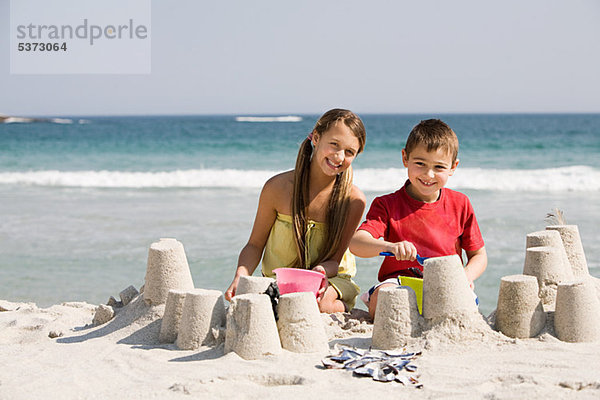 Mädchen und Junge machen Sandburgen am Strand