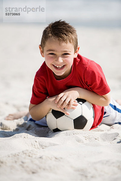 Kleiner Junge mit Fußball am Strand