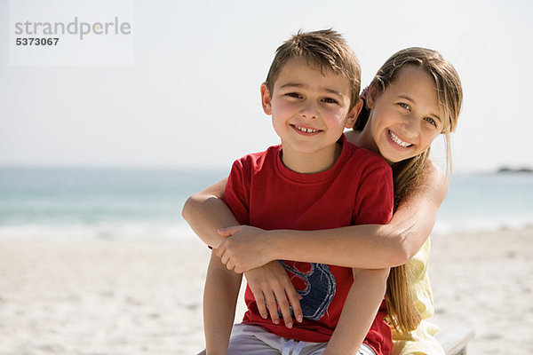 Bruder und Schwester umarmen sich am Strand