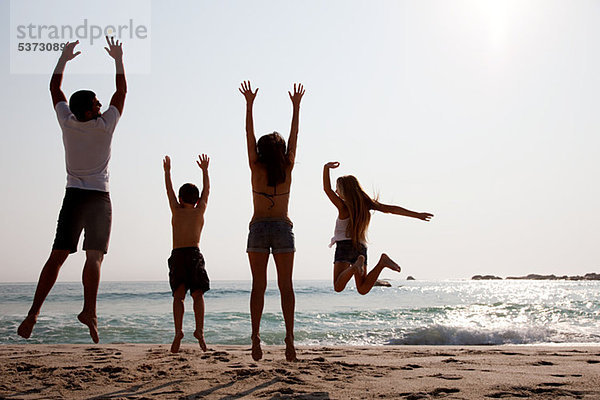 Familie springt am Strand in die Luft