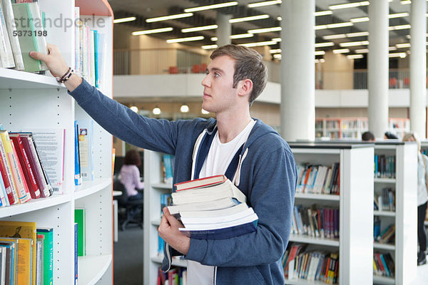 Universitätsstudent wählt Lehrbücher in der Bibliothek aus