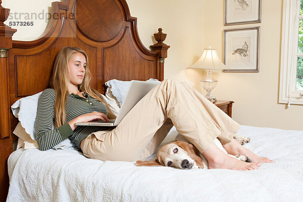 Young Woman relaxing auf Bett mit laptop