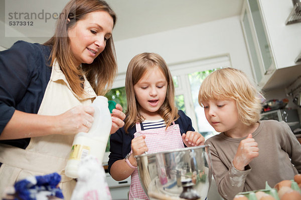 Mittlere erwachsene Frau beim Backen mit Sohn und Tochter in der Küche
