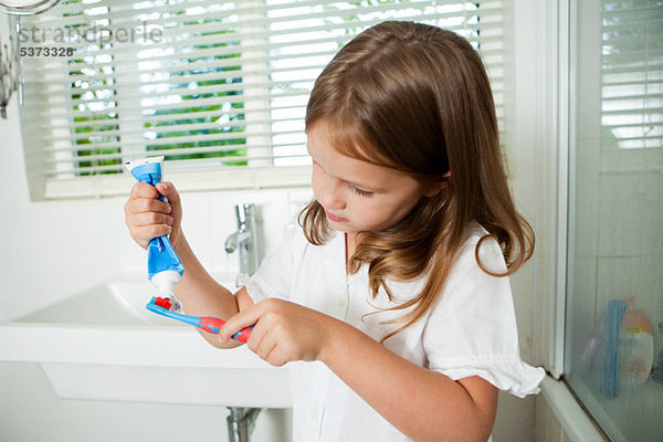 Mädchen beim Auftragen von Zahnpasta auf die Bürste im Bad