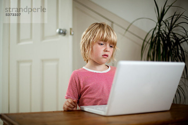 Boy using Laptop auf Schreibtisch