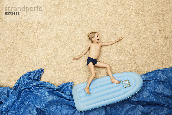 Deutschland  Junge auf Schlauchboot im Wasser am Strand