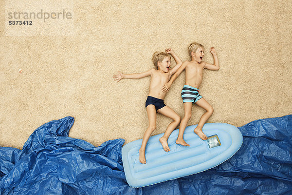 Deutschland  Jungen auf Schlauchboot im Wasser am Strand