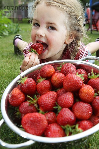 Ein Mädchen mit Erdbeeren in einem Sieb