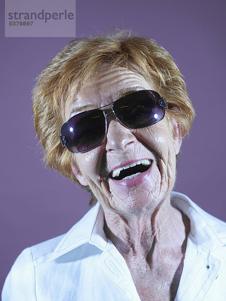 Seniorin lacht vor violettem Hintergrund