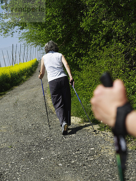 Reife Frau Nordic Walking mit Haltestange für den Mann