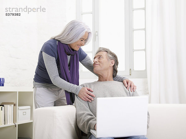 Deutschland  Hamburg  Seniorenpaar mit Laptop schaut sich an  lächelnd