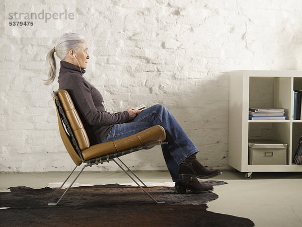 Seniorin auf dem Stuhl sitzend und Musik hörend