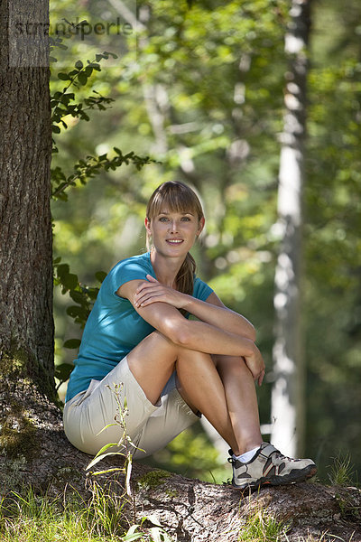 Deutschland  Oberbayern  Junge Frau unter Baum  lächelnd  Porträt