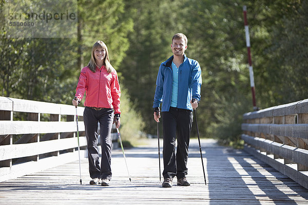 Deutschland  Oberbayern  Paar mit Nordic Walking auf der Brücke