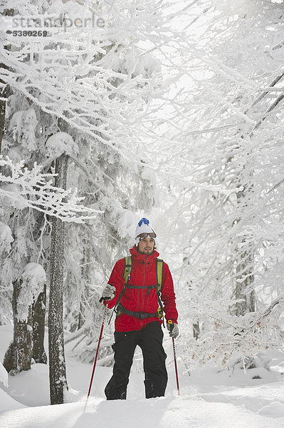 Junger Mann beim Telemark-Skifahren im Bergwald Herzogstand