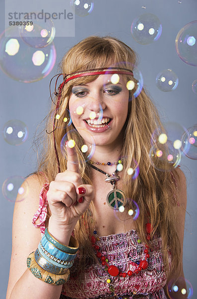 Junge Hippie-Frau mit Blasen auf grauem Hintergrund  lächelnd  Mund