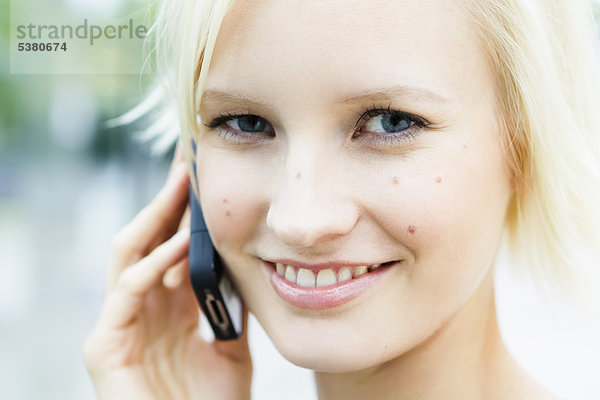 Junge Frau am Telefon  lächelnd  Portrait